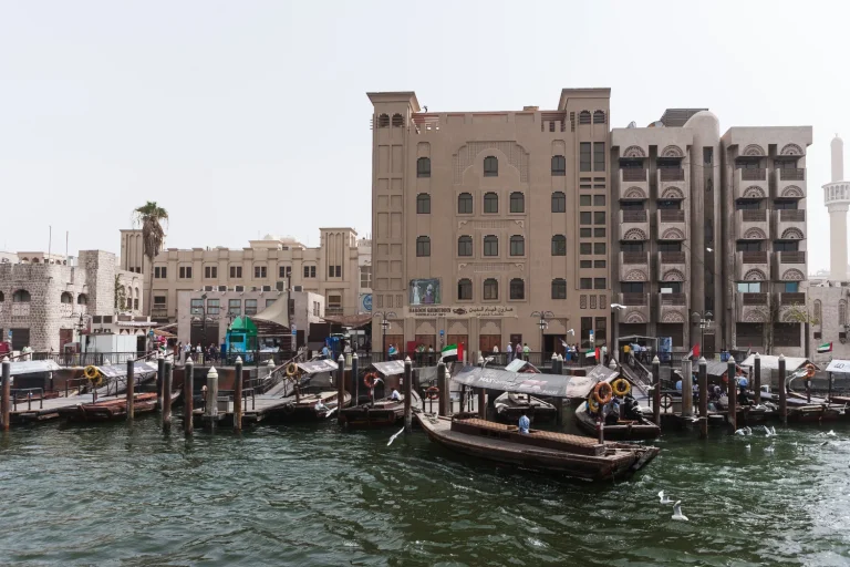 Abra boats moored on Dubai Creek in front of old souk buildings