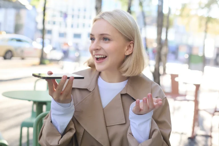 Woman at an outdoor cafe speaking into her phone held flat